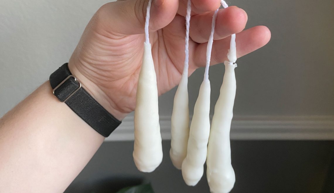 Hand holding four homemade hand dipped candles